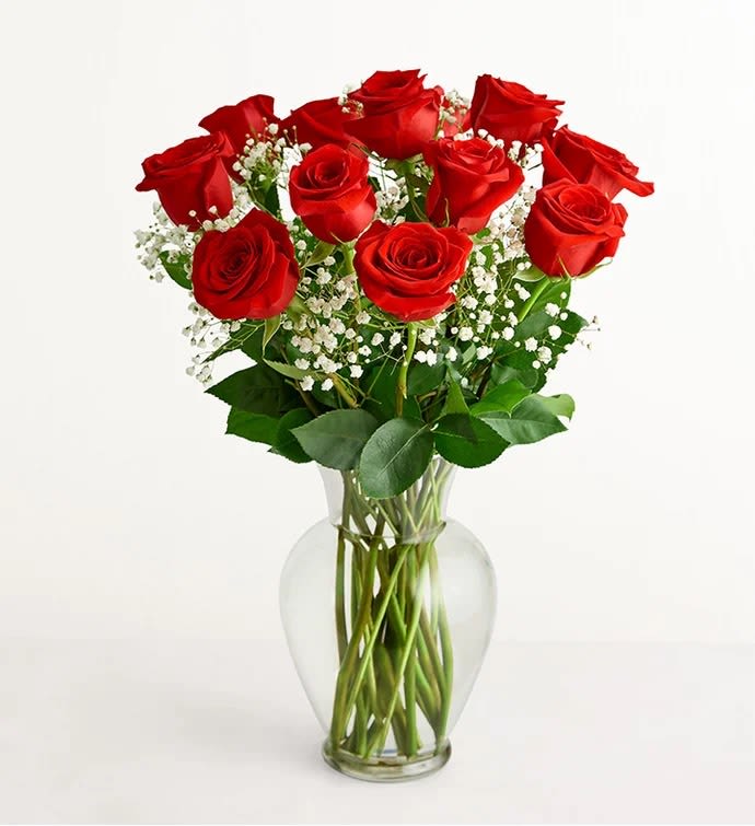 Red roses arranged in a clear glass vase with white baby's breath