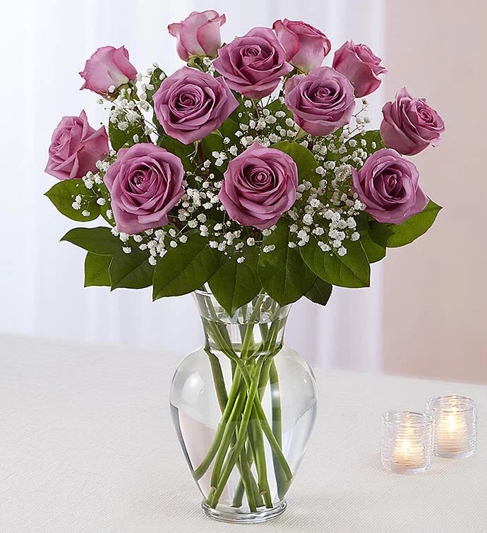 Lavender roses arranged in a clear glass vase with baby's breath