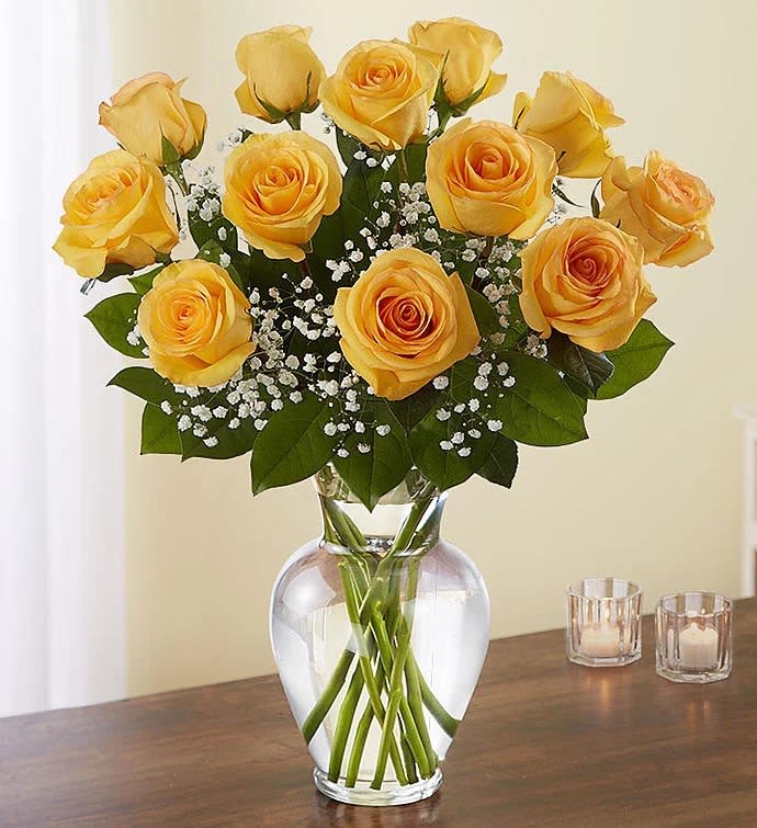 Yellow roses arranged in a clear glass vase with baby's breath