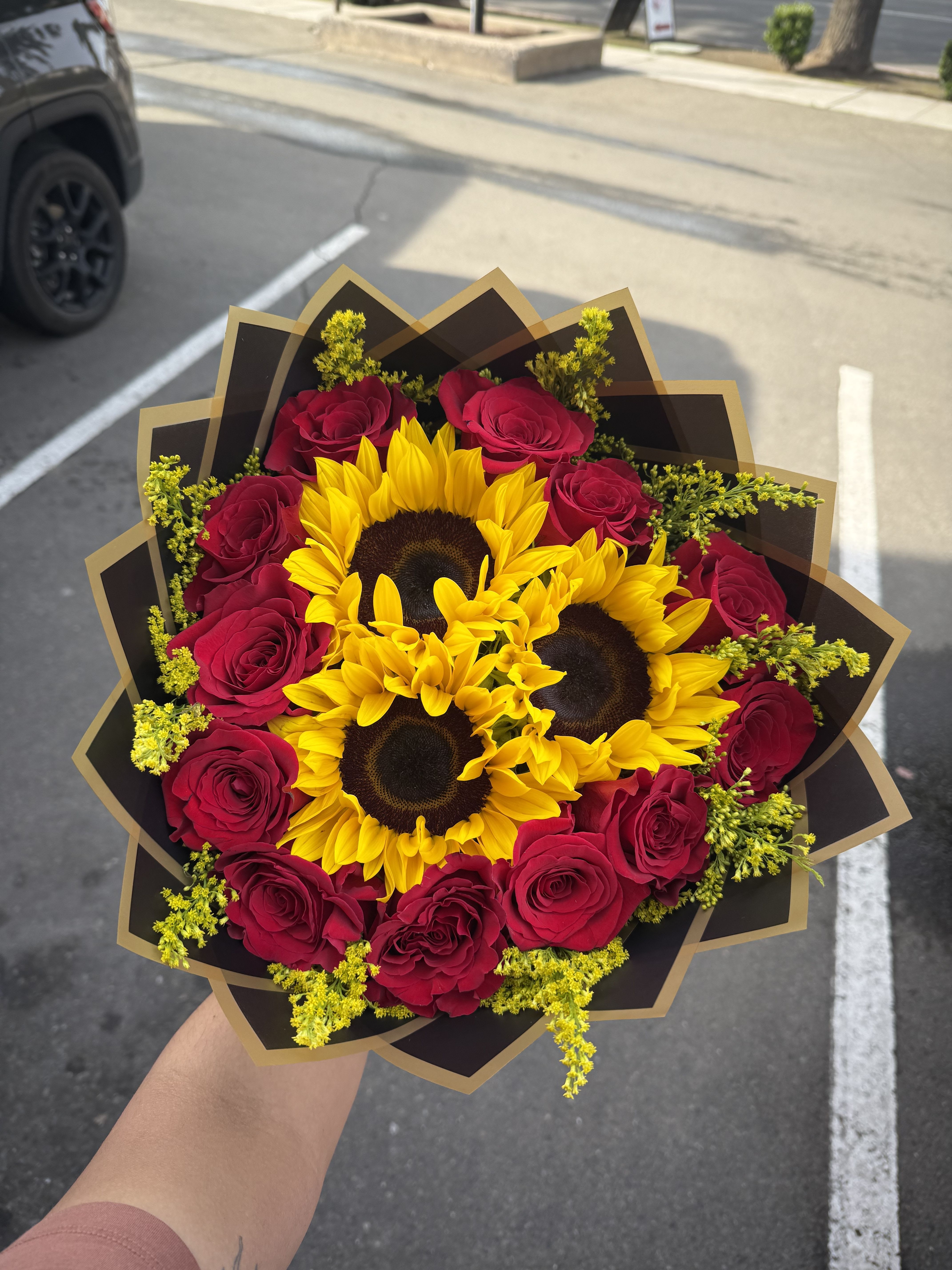 Bouquet of red roses and sunflowers wrapped in black paper