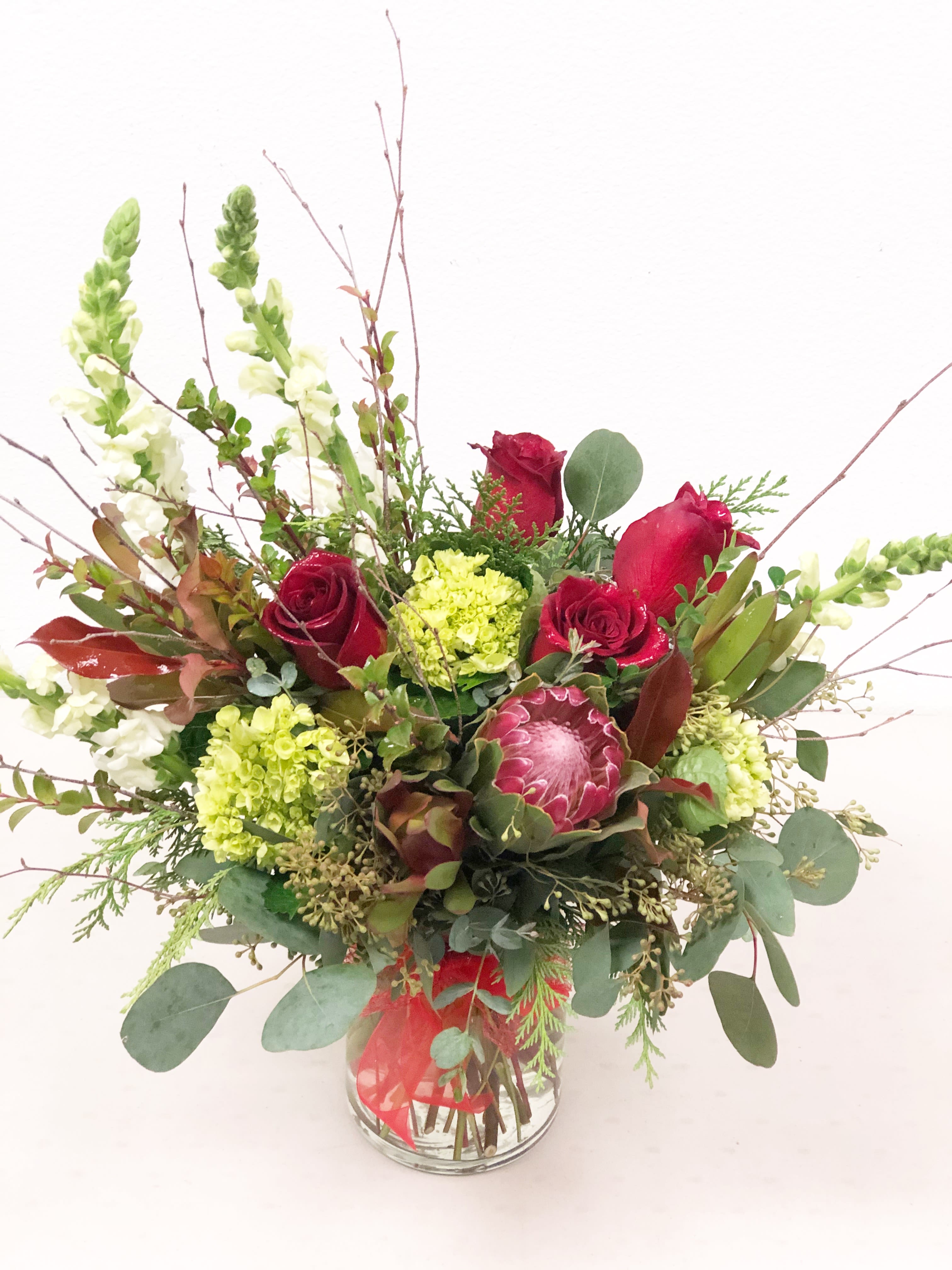 Bouquet of red roses and green blooms in a glass vase