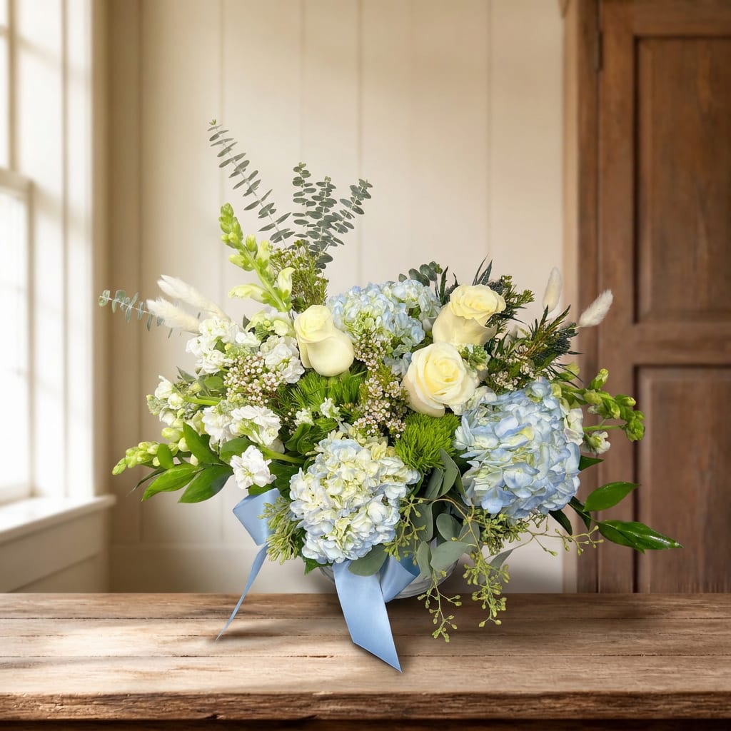 Blue and white floral arrangement in a vase with a ribbon
