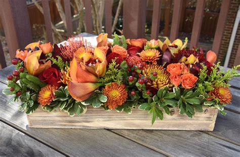 Autumn Breeze  - A stunning modern centerpiece for Thanksgiving. In a beautiful wood rectangle container, it is a natural element for your holiday table. The autumn-colored flowers compliment the natural wood &amp; make for a beautiful centerpiece.