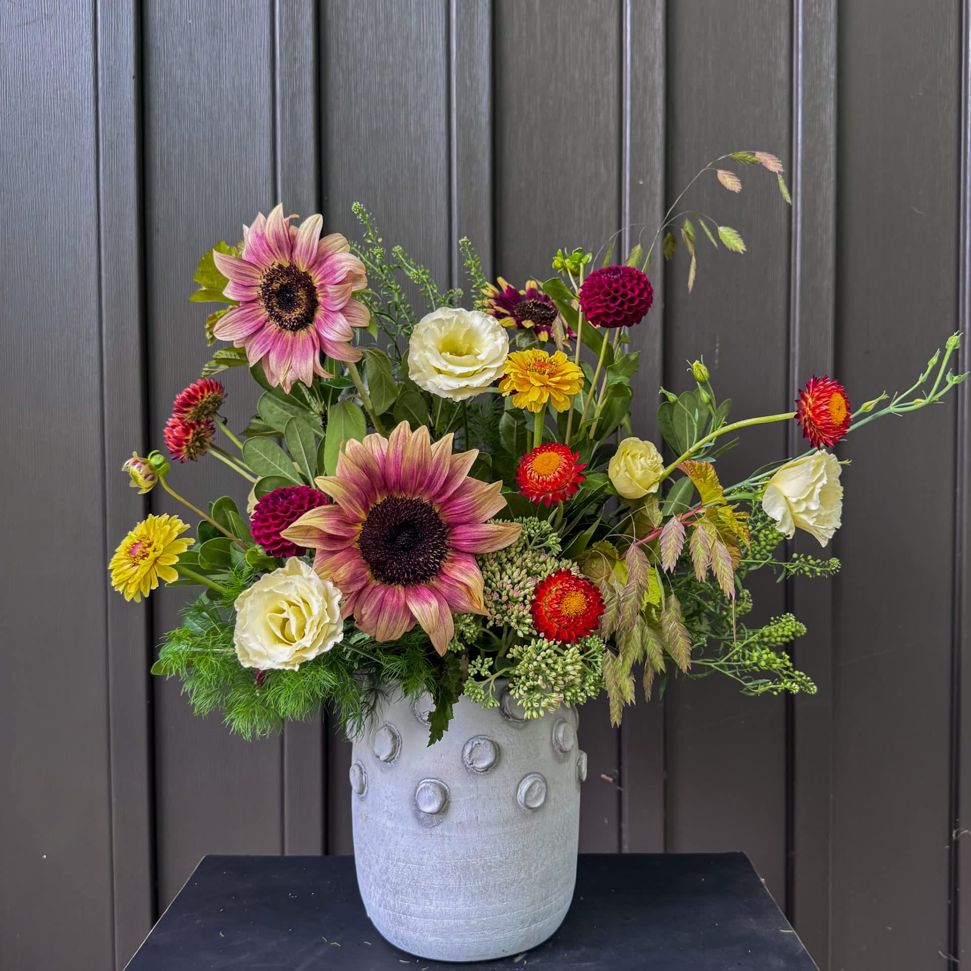 Mixed bouquet with sunflowers and white blooms in a gray vase