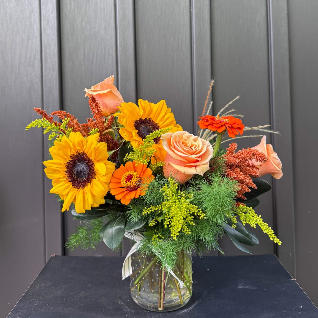 Sunflower and peach rose bouquet in a glass vase