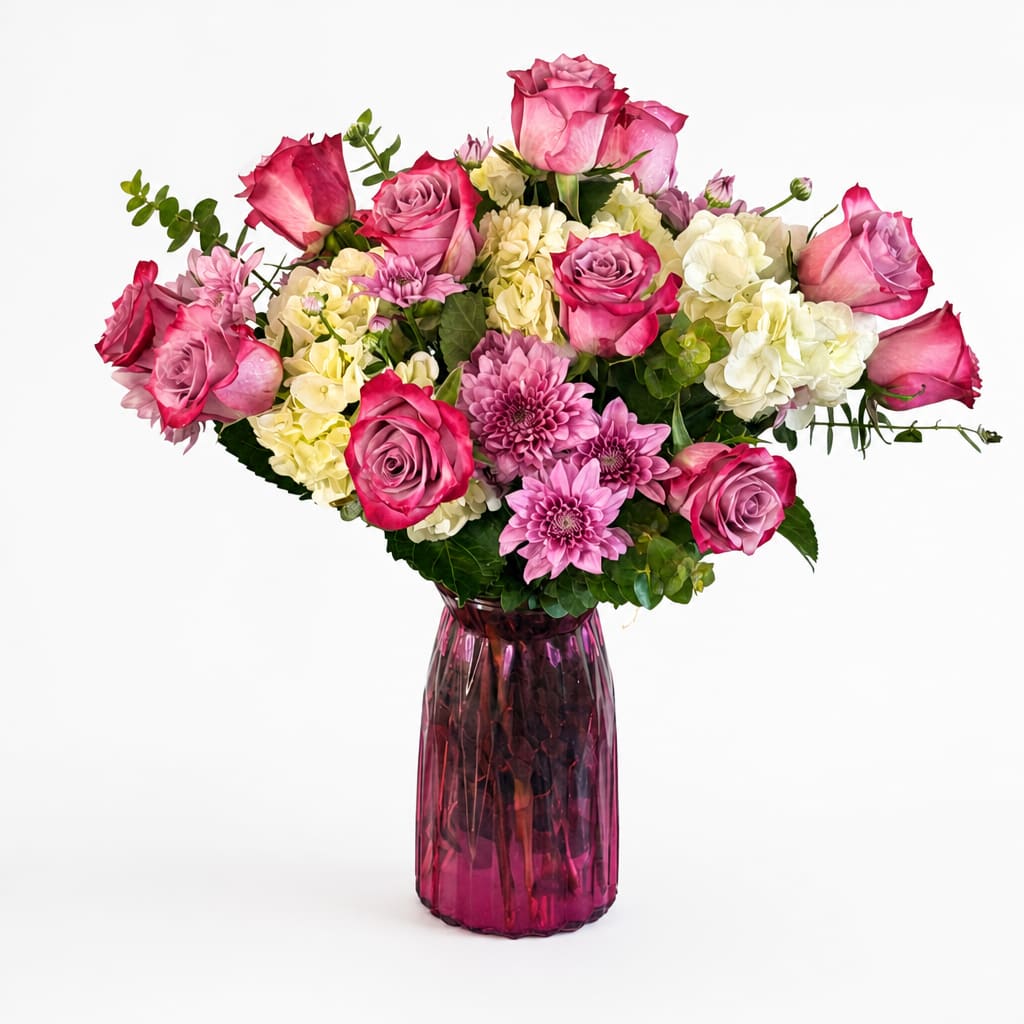 Pink and white mixed flower bouquet in a purple glass vase