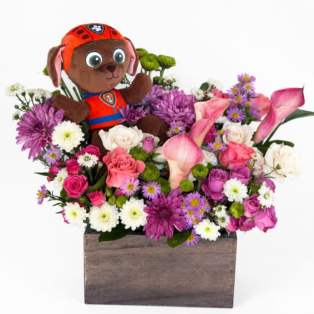 Plush puppy in a flower arrangement with pink calla lilies and mixed blooms in a wooden box