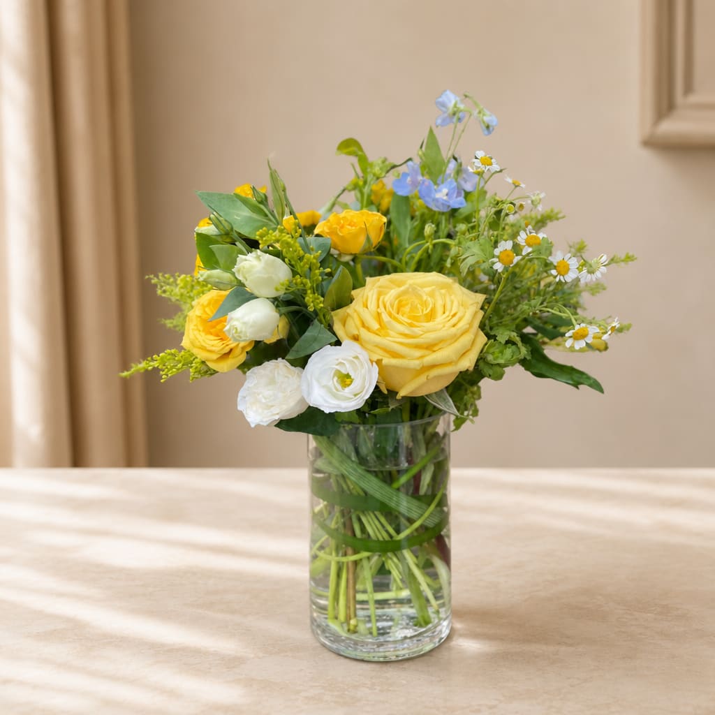 Yellow and white flowers arranged in a clear glass vase