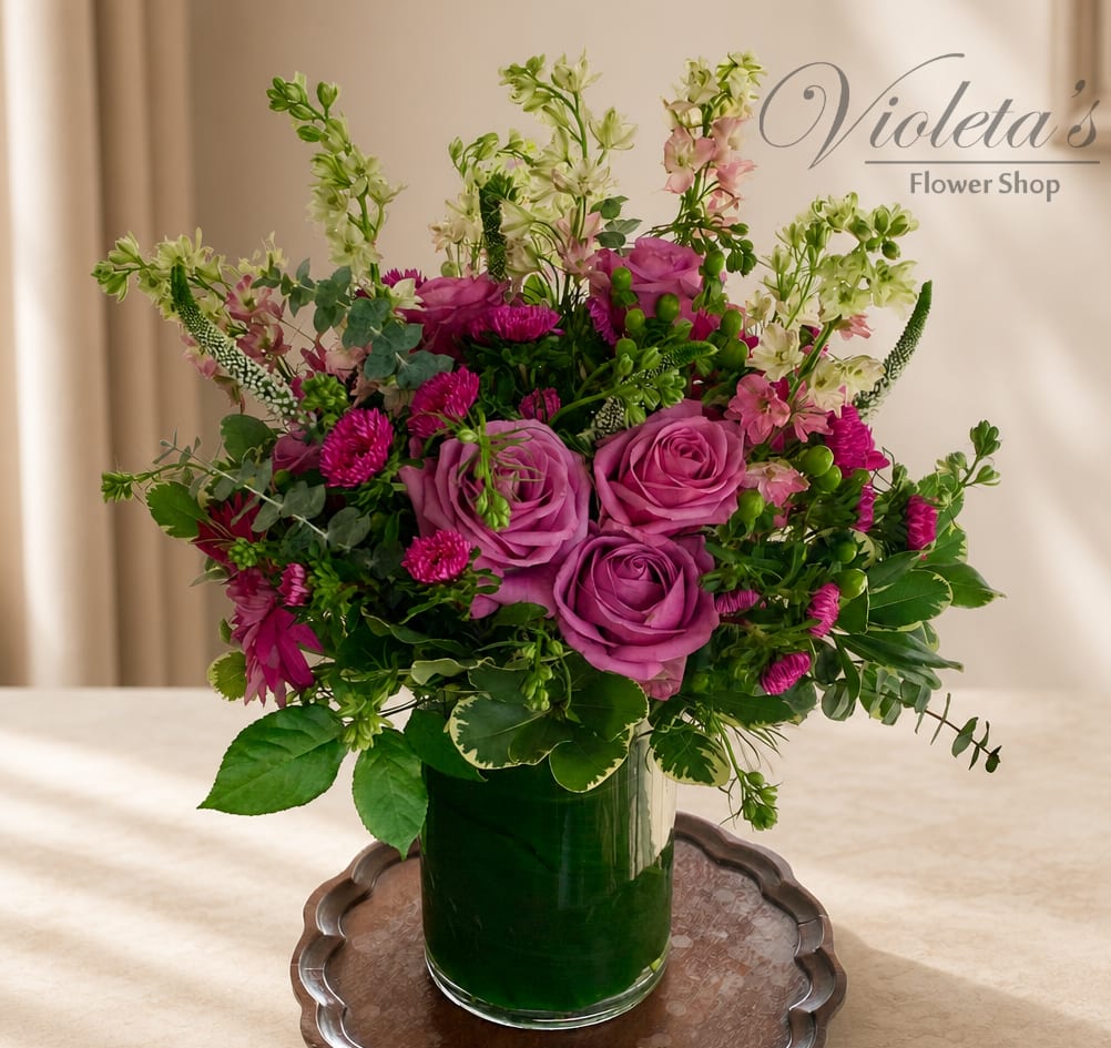 Pink and purple roses with mixed flowers in a glass vase