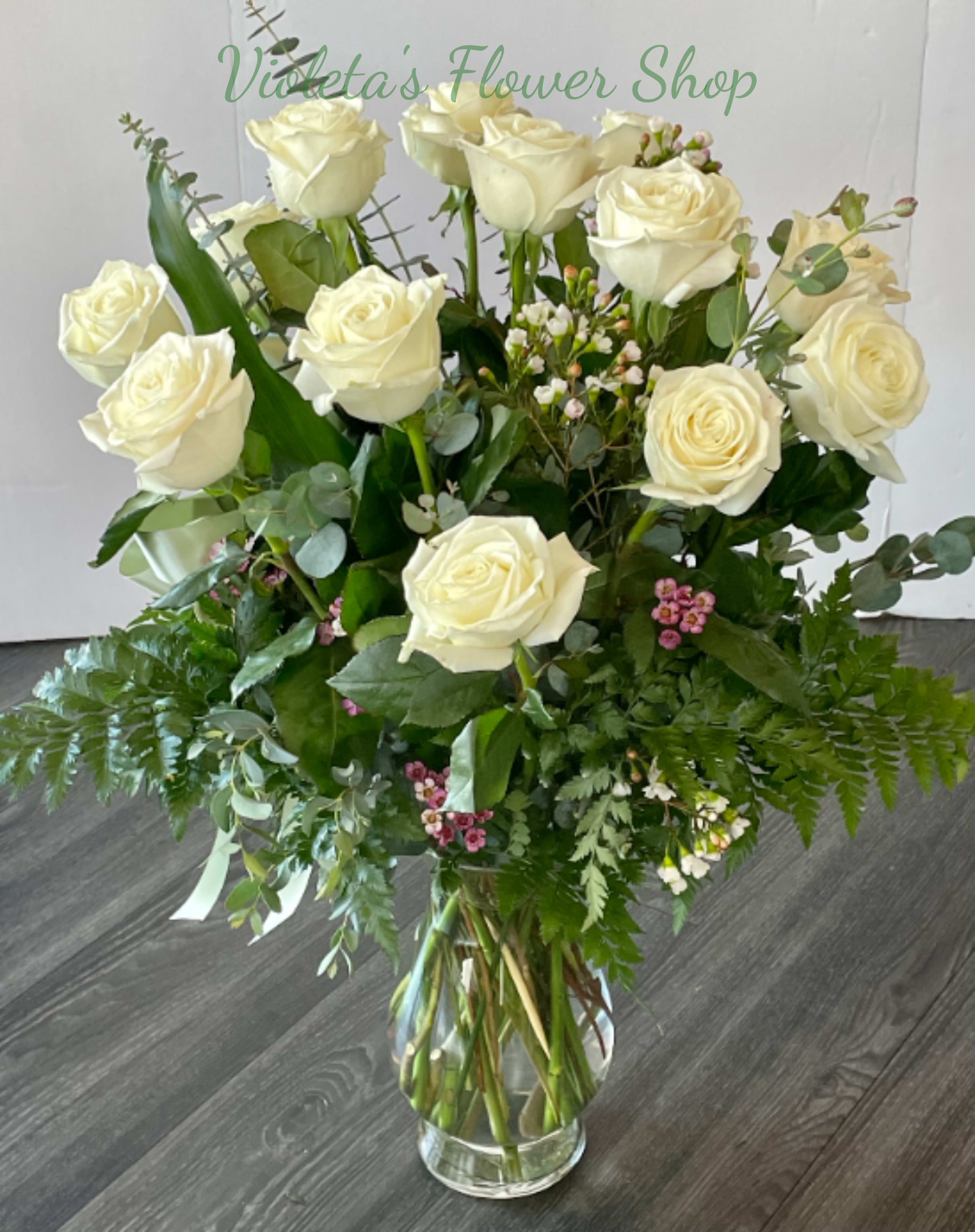 Bouquet of white roses in a clear glass vase with mixed greenery