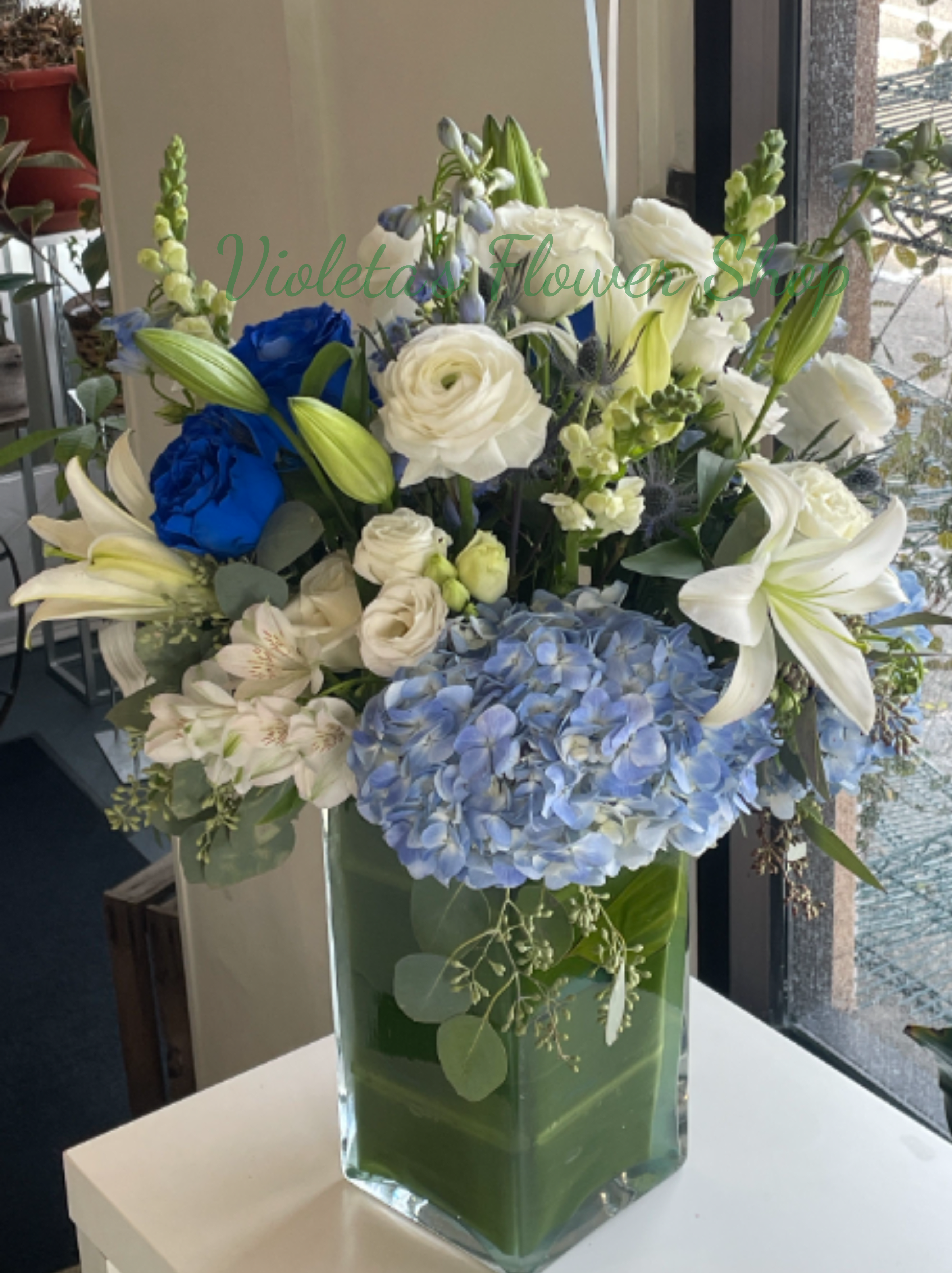 Blue and white floral arrangement in a clear glass vase