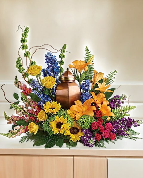 Colorful floral arrangement around a copper urn