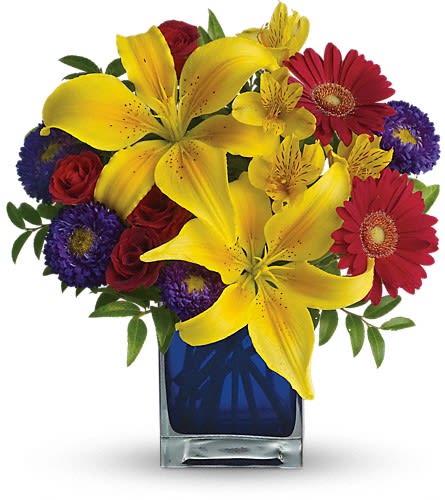 Bouquet of yellow lilies, red roses, and purple daisies in a blue glass vase
