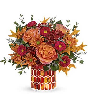 Autumn Aglow Bouquet - Artfully arranged in a beautiful keepsake vase of stained glass mosaic, this magnificent rose bouquet celebrates the special magic of fall. This beautiful bouquet includes orange roses, red matsumoto asters, bronze cushion spray chrysanthemums, bronze daisy spray chrysanthemums, purple limonium and parvifolia eucalyptus, accented with preserved oak leaves. Delivered in Teleflora's Autumn Radiance Mosaic vase. Orientation: All-Around 