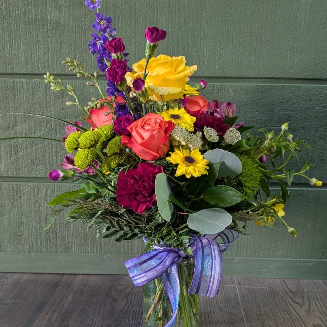 Colorful mixed bouquet with roses, daisies, and purple blooms tied with a ribbon