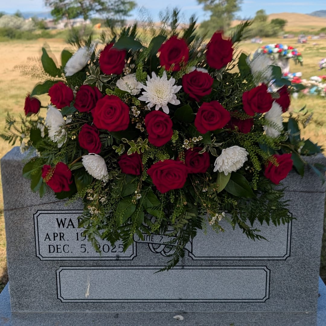 Red rose and white chrysanthemum arrangement on a gravestone