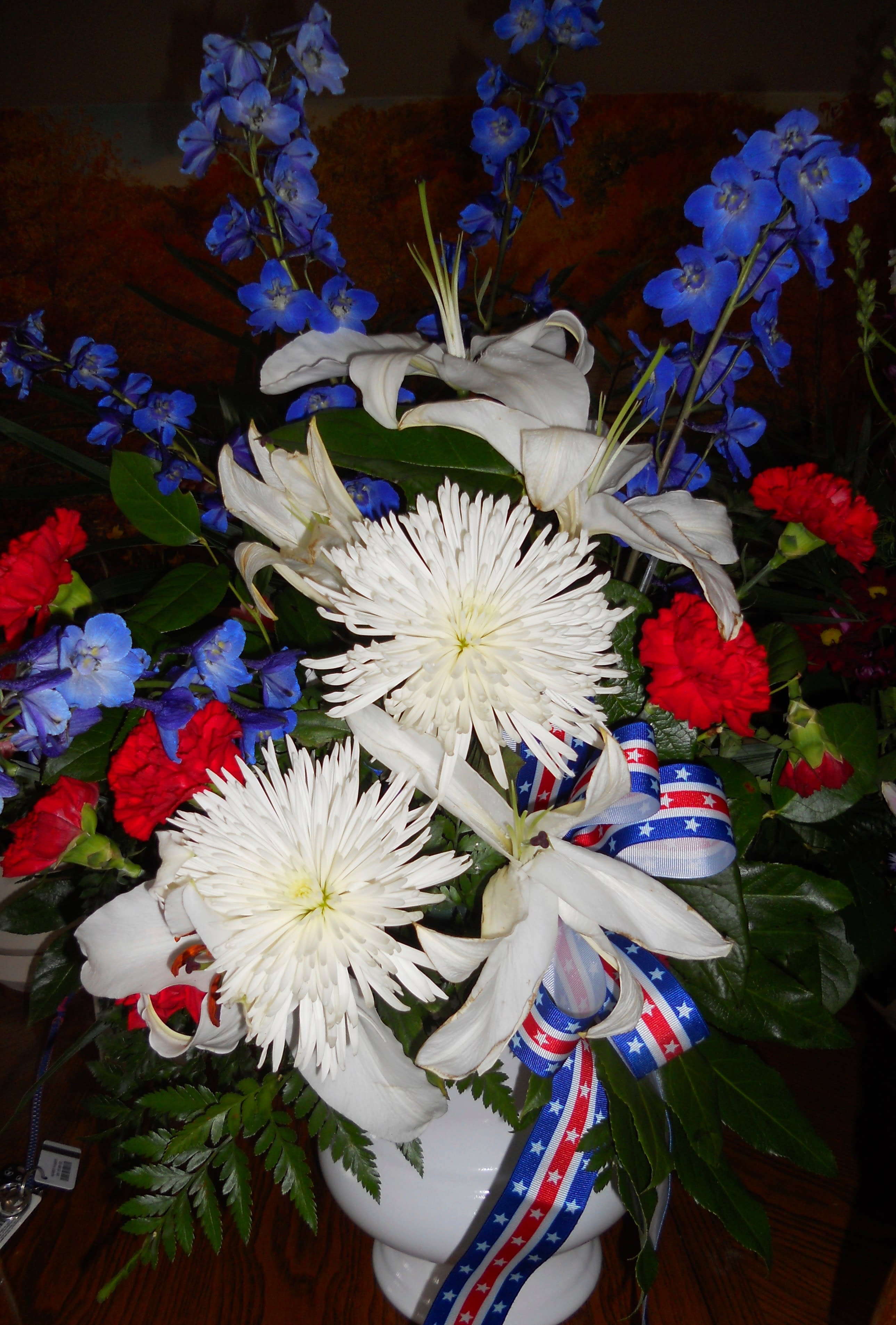 White lilies and chrysanthemums with blue and red flowers in a white vase