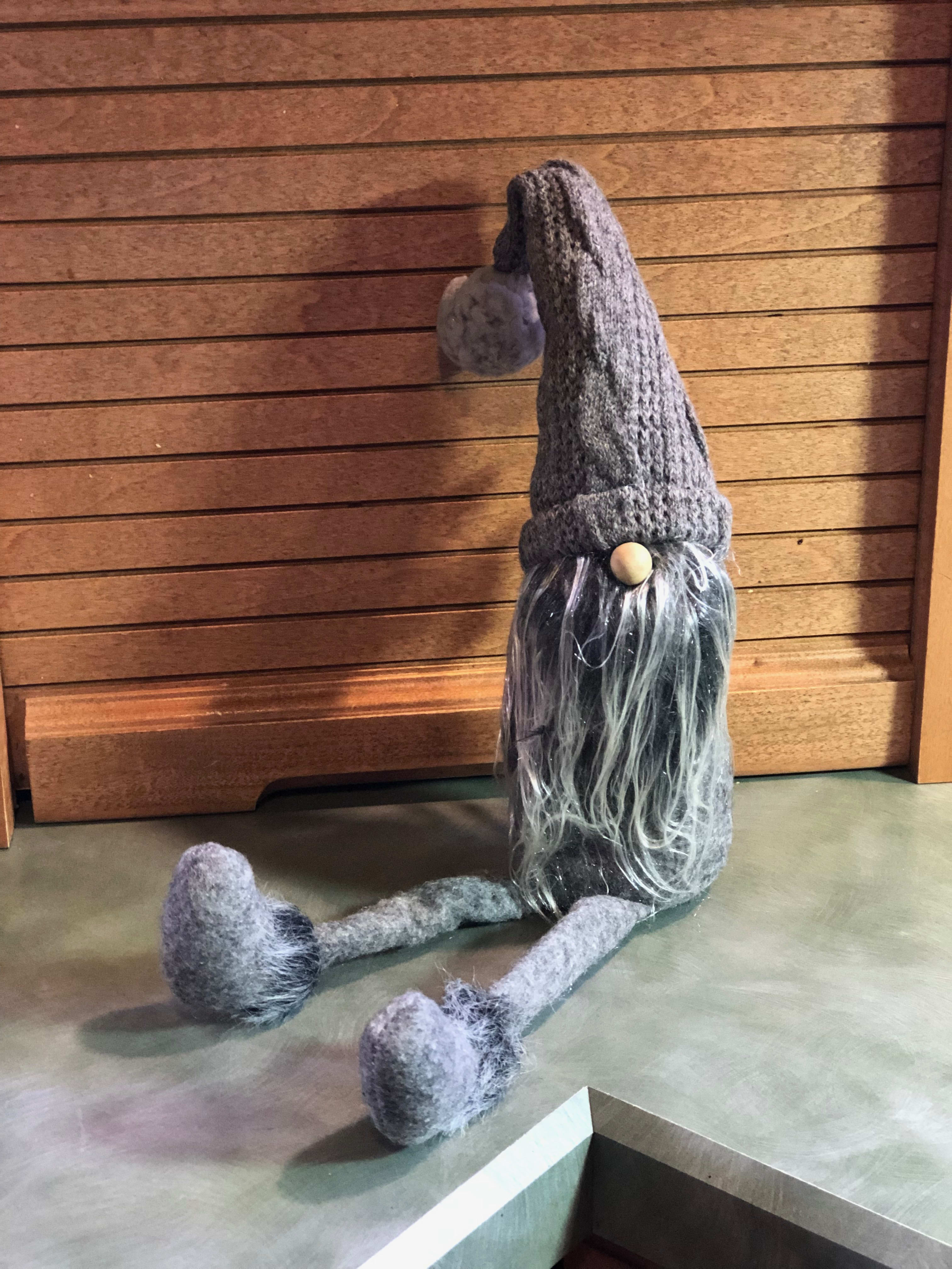 Knitted gnome figurine with long gray beard and dangling legs