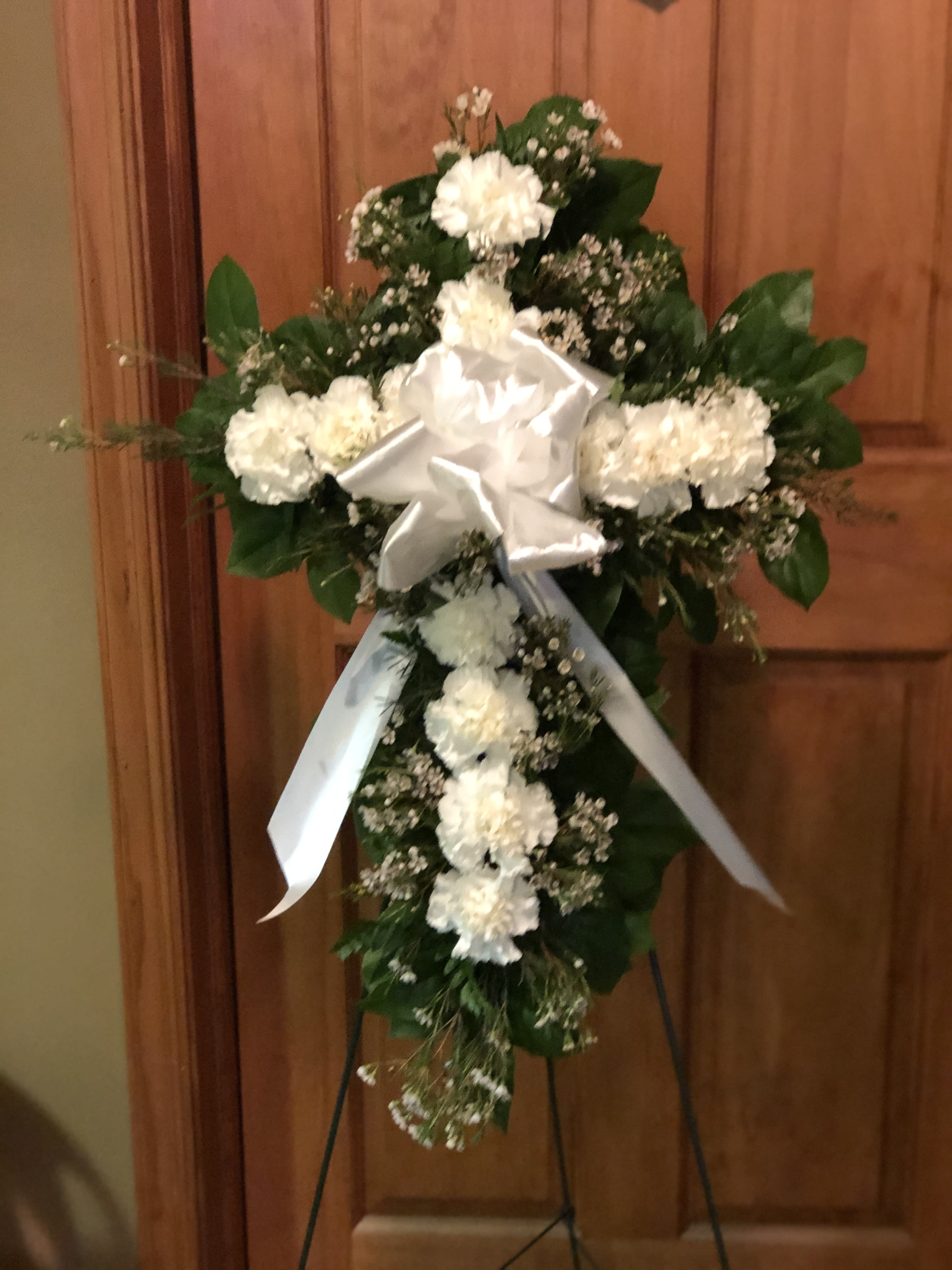 Carnation Cross - Our Carnation Cross is highlighted with a dozen carnations with greenery and filler on 20" foam cross with an easel stand with a simple bow.