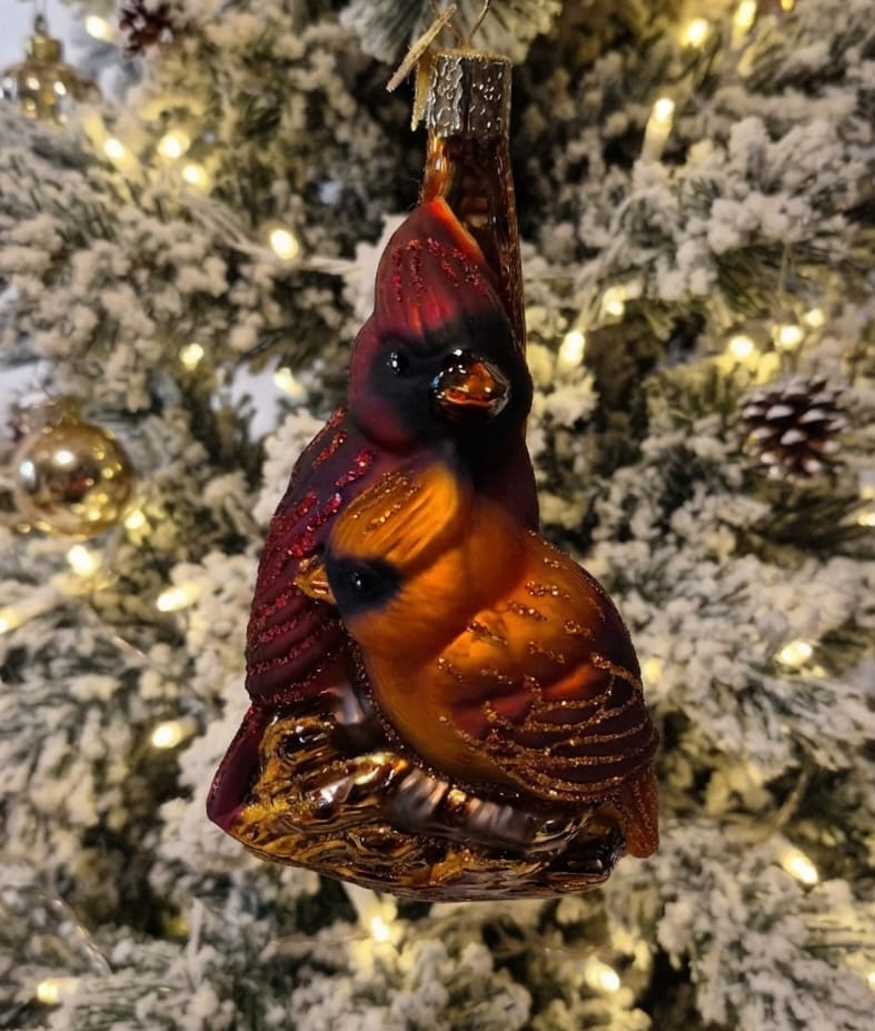 Cardinal ornament hanging on a snowy Christmas tree