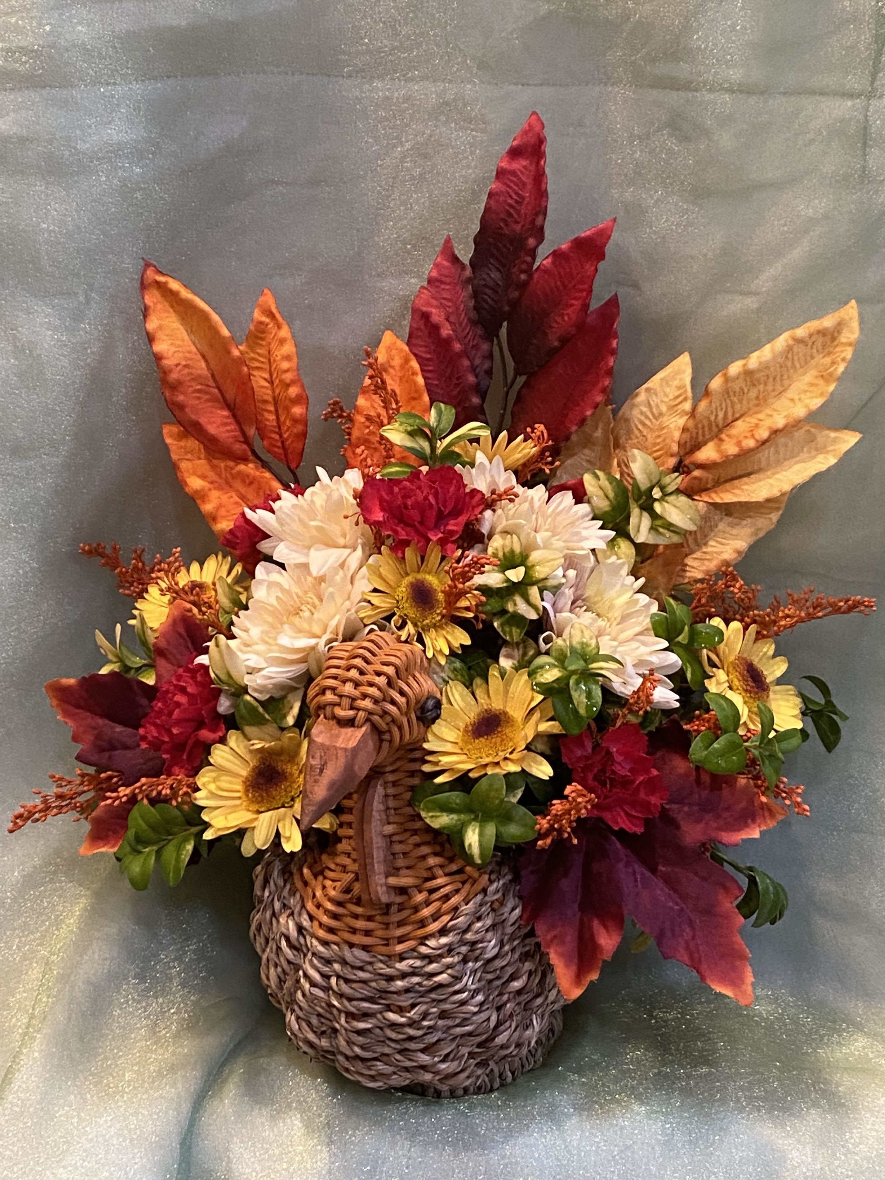 Tom the Turkey  - A woven turkey basket filled with bright fall blooms and colorful autumn foliage.