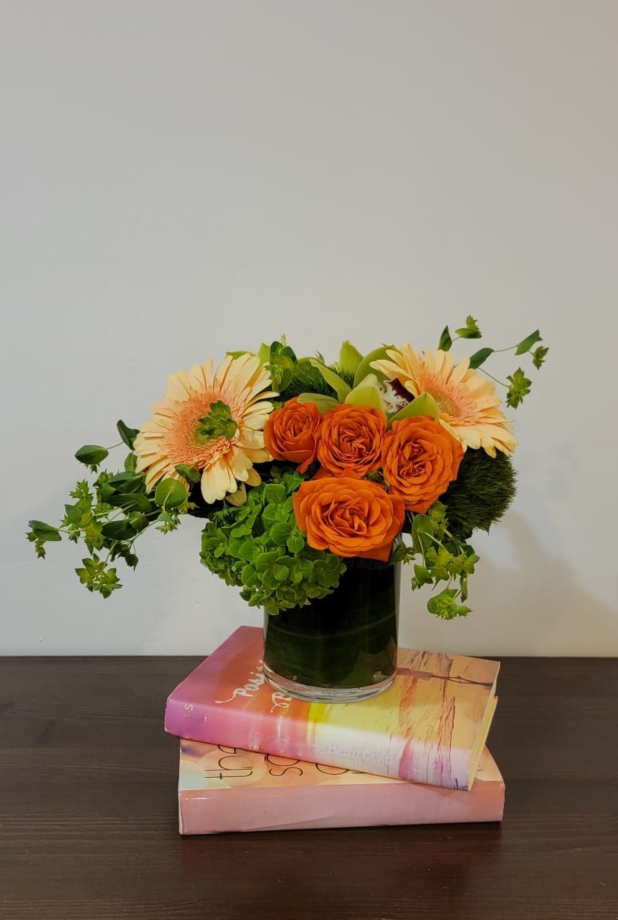 Orange roses and pale peach gerbera daisies in a glass vase