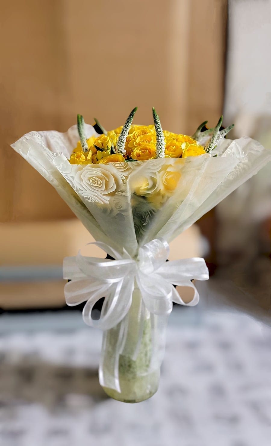 Yellow rose bouquet wrapped in white paper with a ribbon