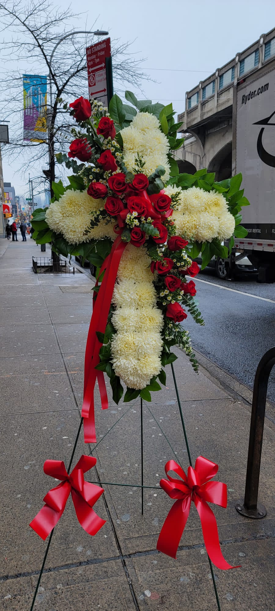 Standing floral cross with red roses and white mums on an easel