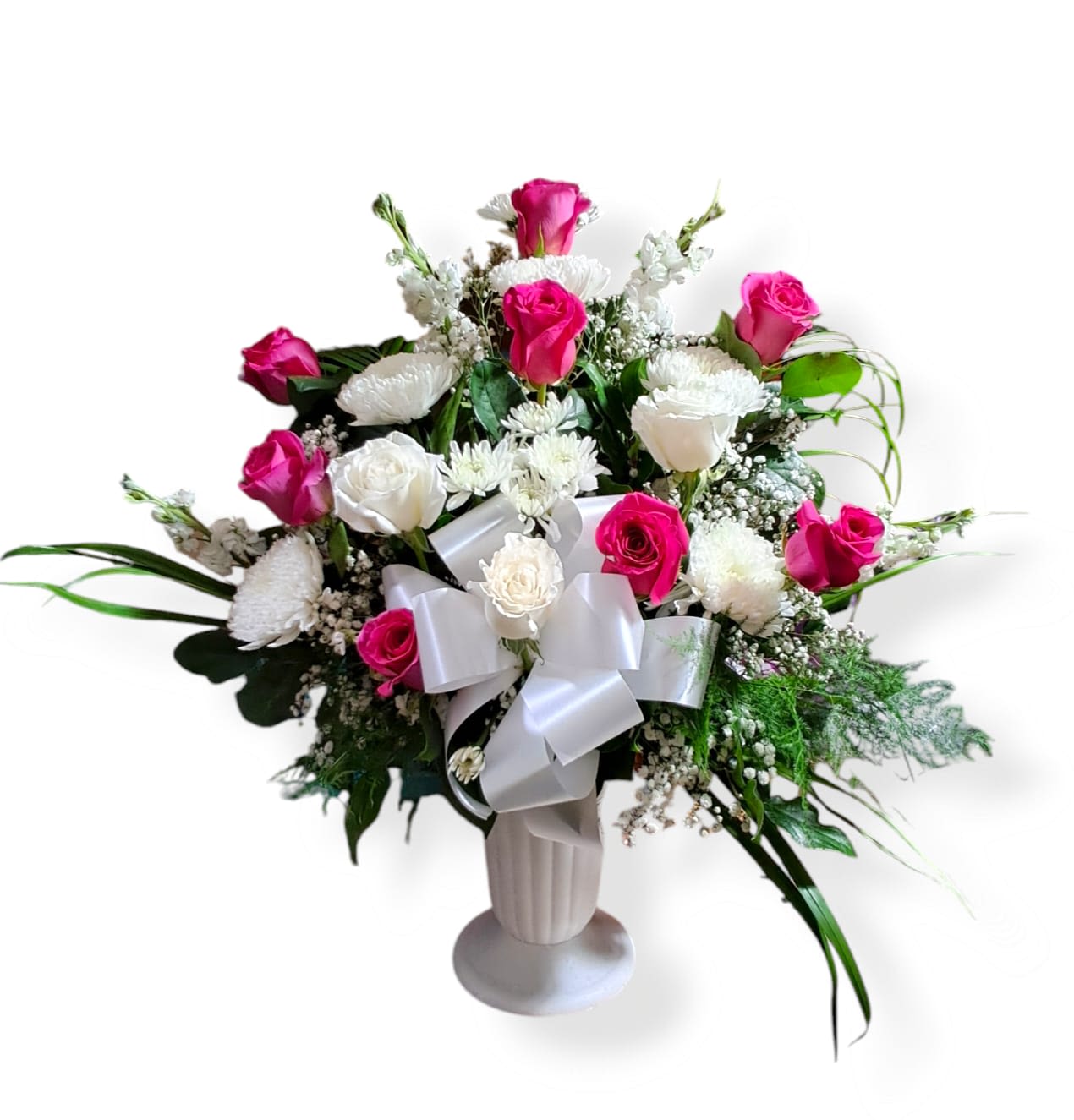 Pink and white rose arrangement in a white vase with a satin bow