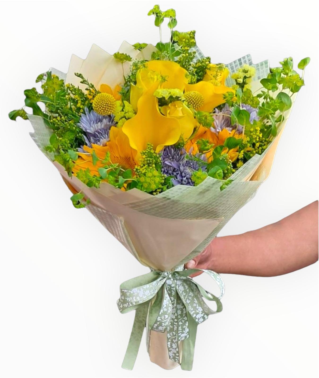 Hand-tied bouquet of yellow and purple flowers wrapped in pale paper
