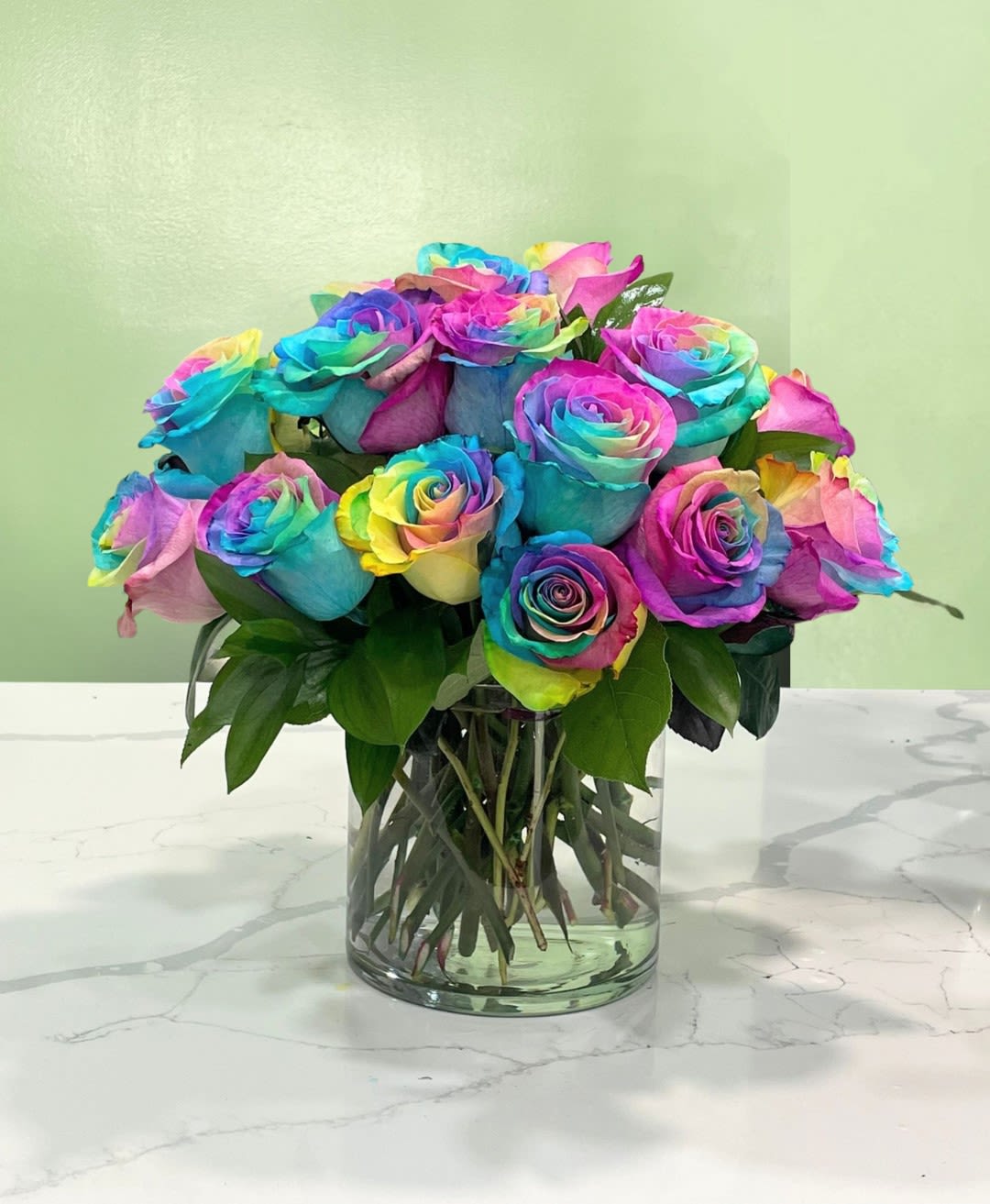Rainbow roses arranged in a clear glass vase