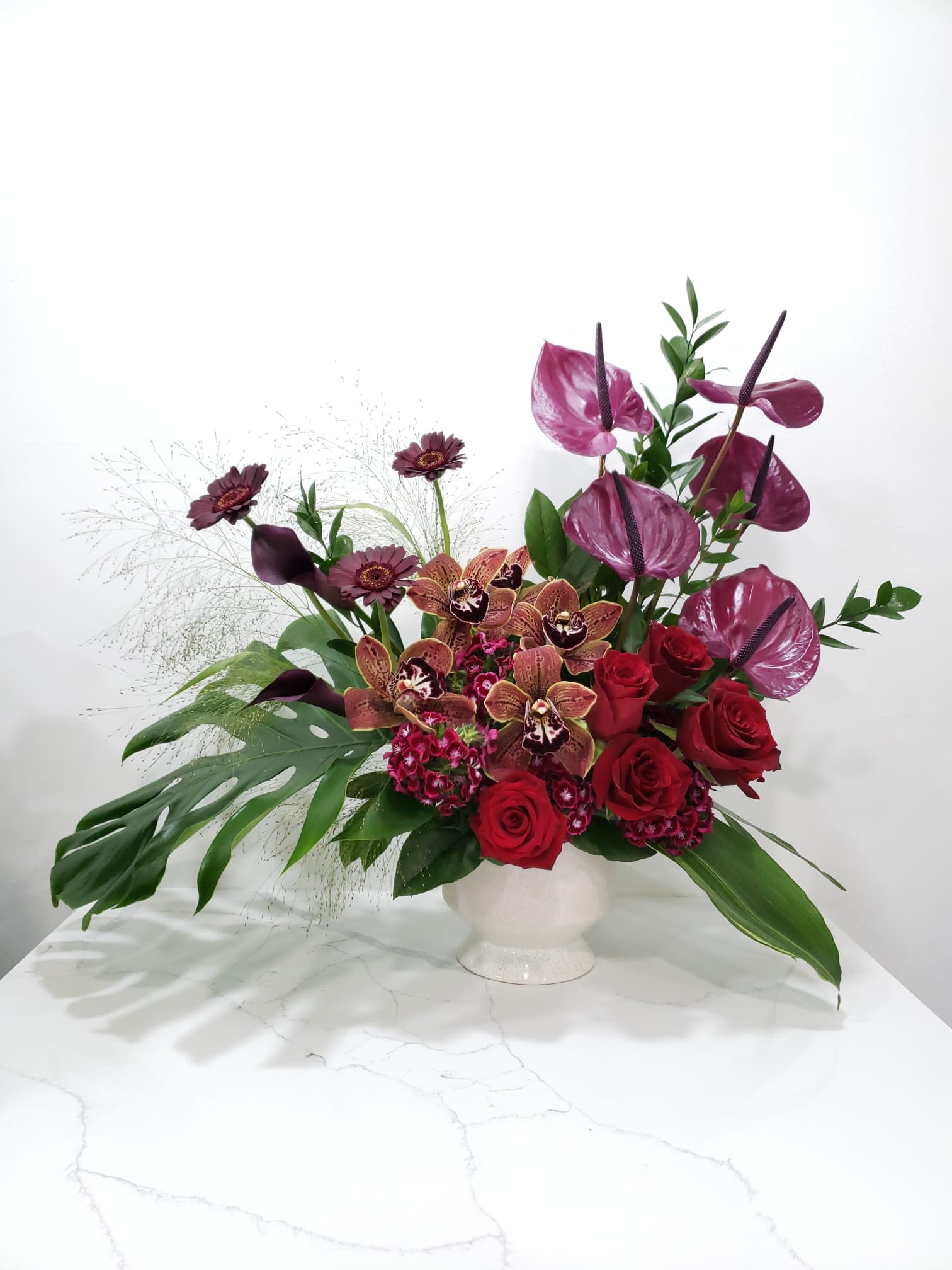 Red roses and purple orchids in a white vase