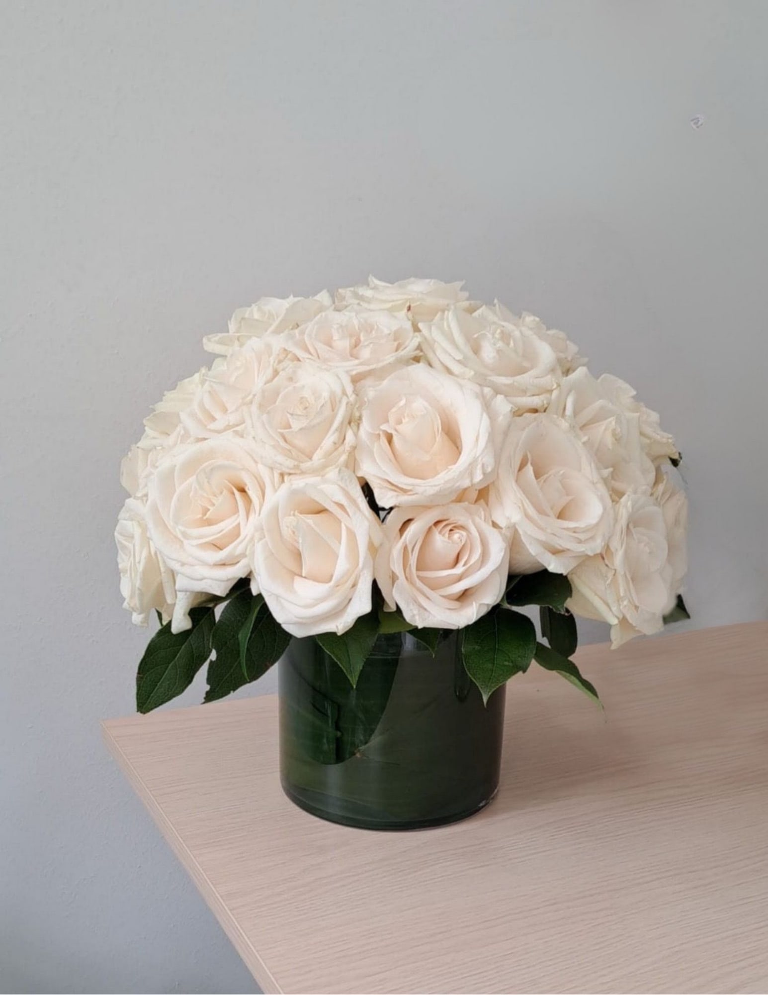 Cream rose bouquet in a dark glass vase