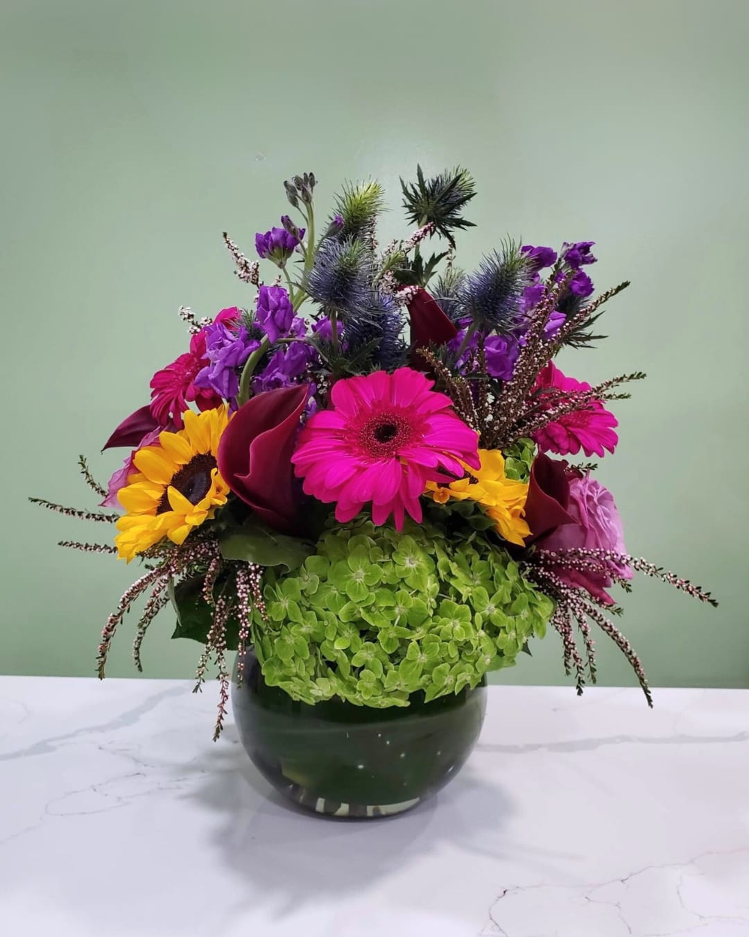 Bright mixed flower arrangement in a dark glass vase