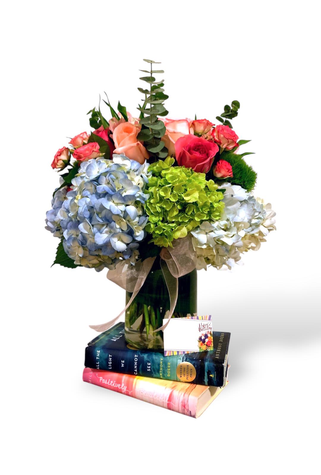 Bouquet of hydrangeas and roses in a glass vase with books underneath