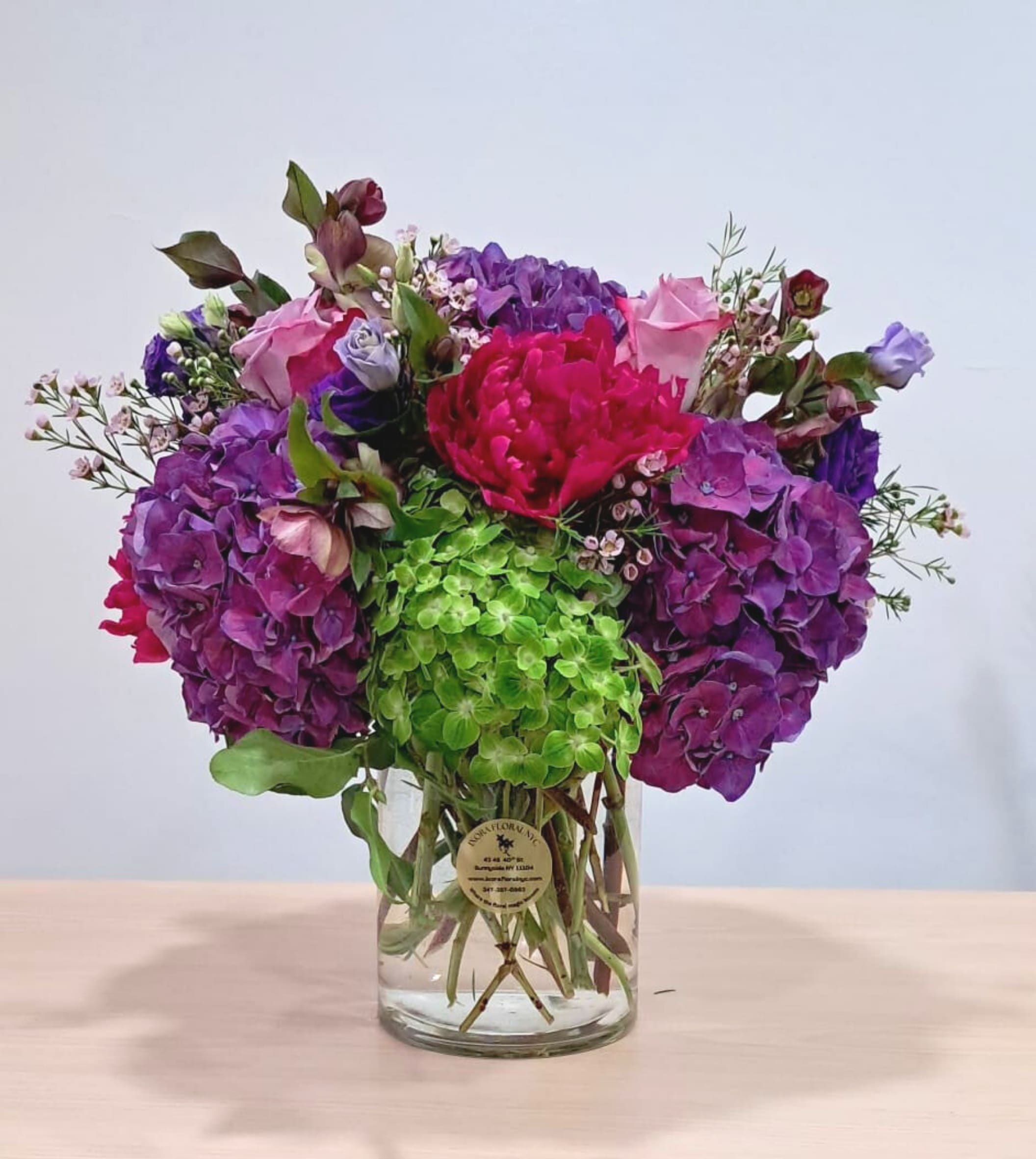 Colorful bouquet of purple, pink, and green flowers in a clear glass vase