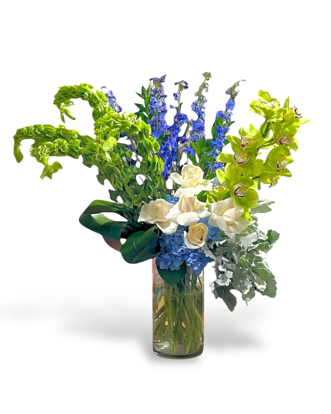 Tall bouquet of blue, white, and green flowers in a glass vase