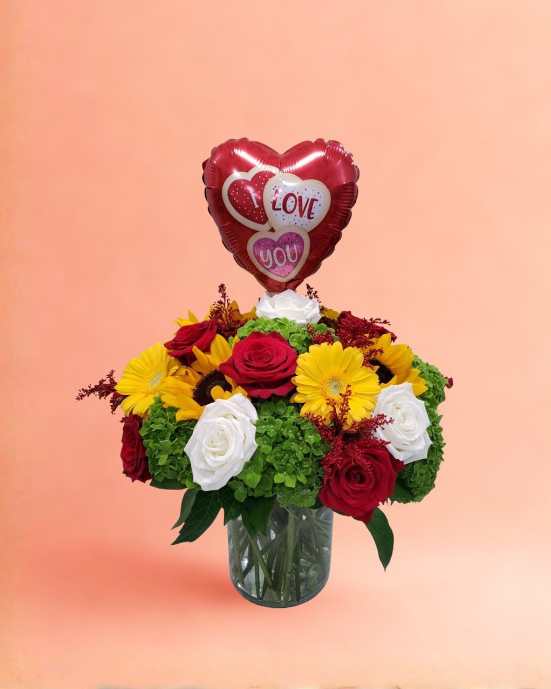 Bouquet of red, white, and yellow flowers with a heart-shaped love balloon in a glass vase