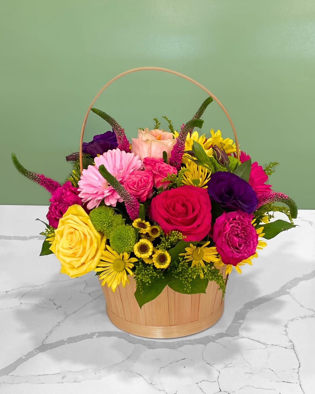 Mixed bouquet in a wooden basket with pink, yellow, and purple flowers