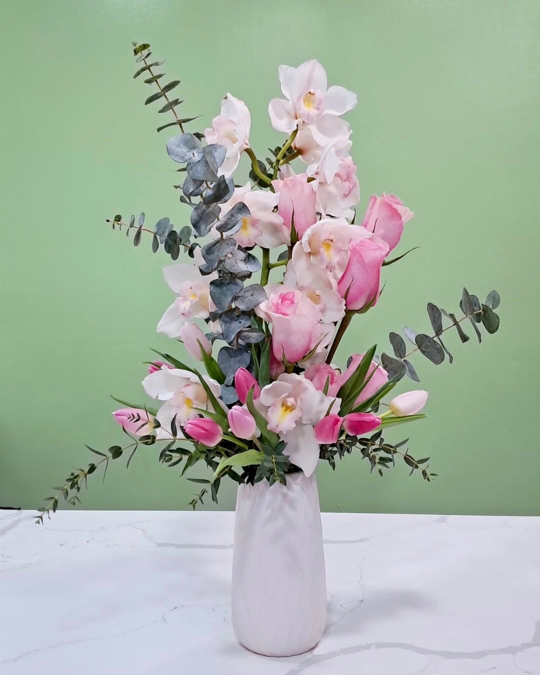 Pink and white orchid arrangement in a white vase
