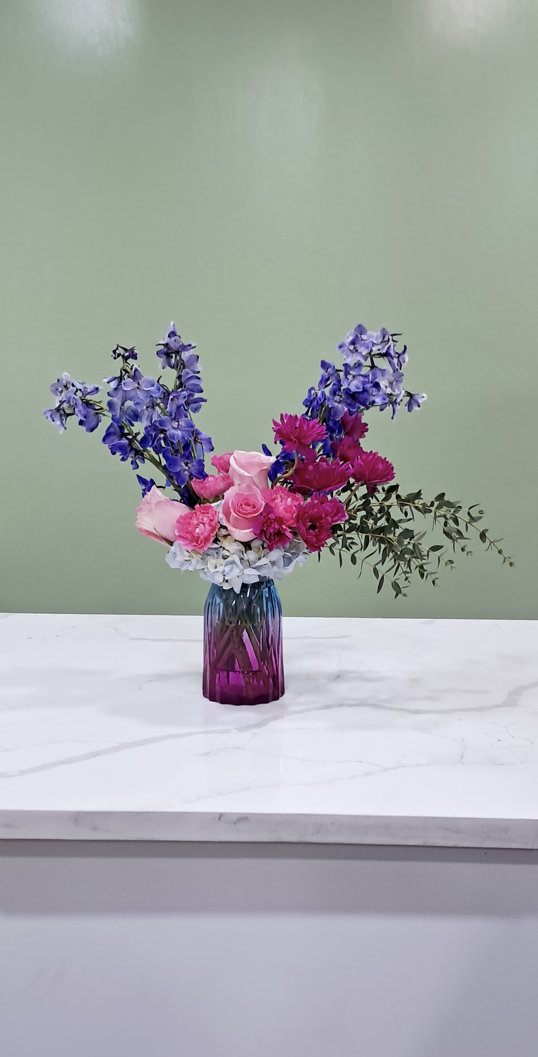Pink and purple flower arrangement in a purple glass vase