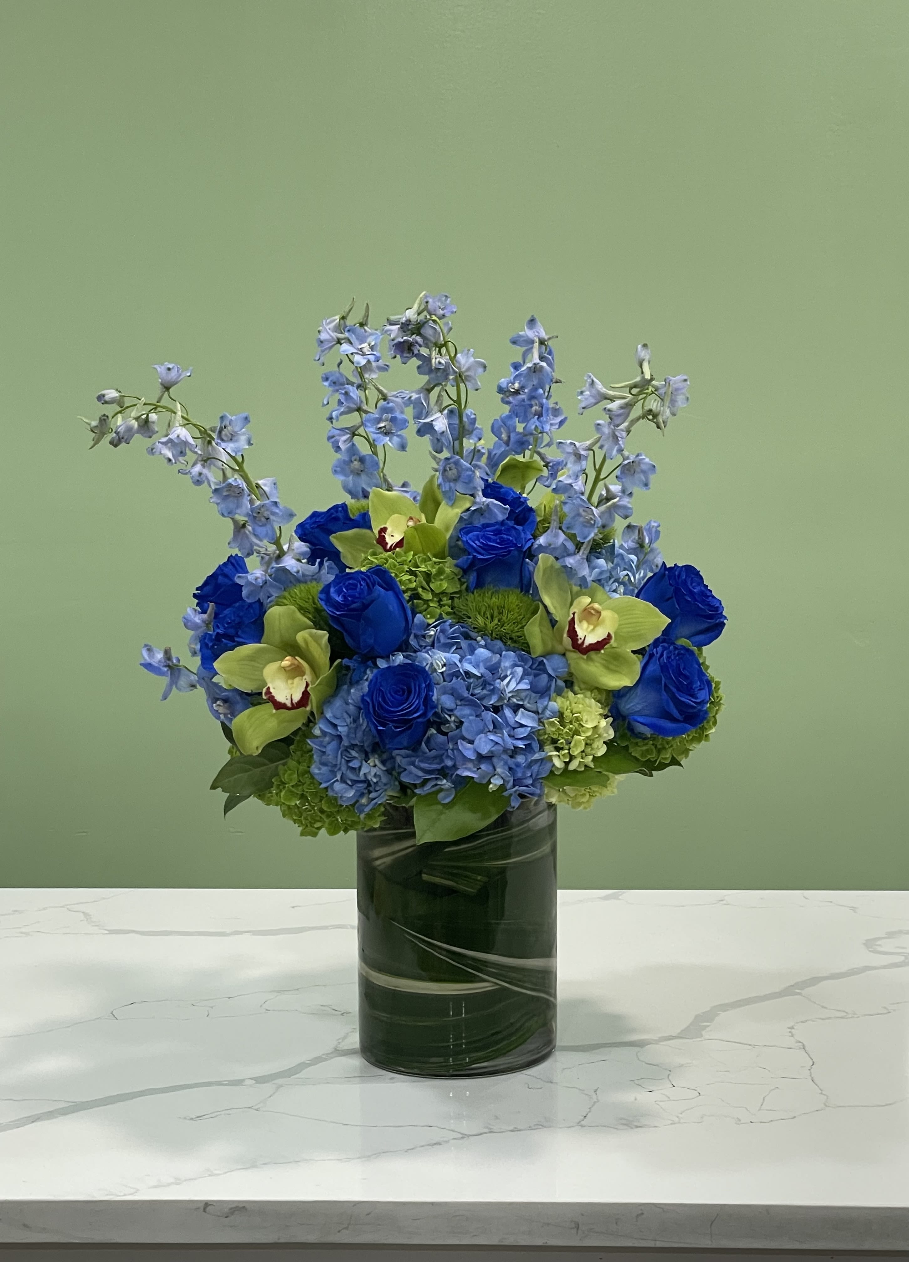 Blue and green floral arrangement in a glass vase