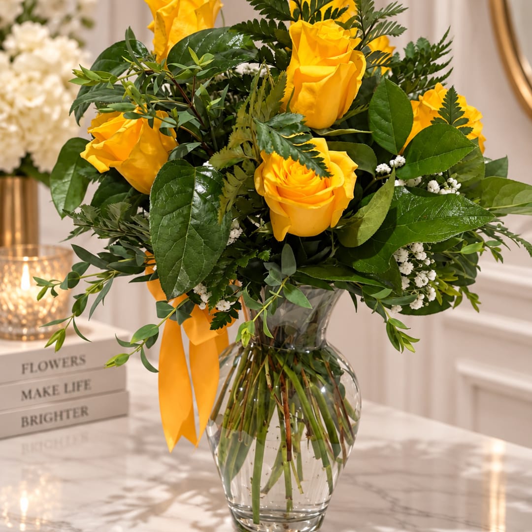 Yellow roses in a clear glass vase with a yellow ribbon