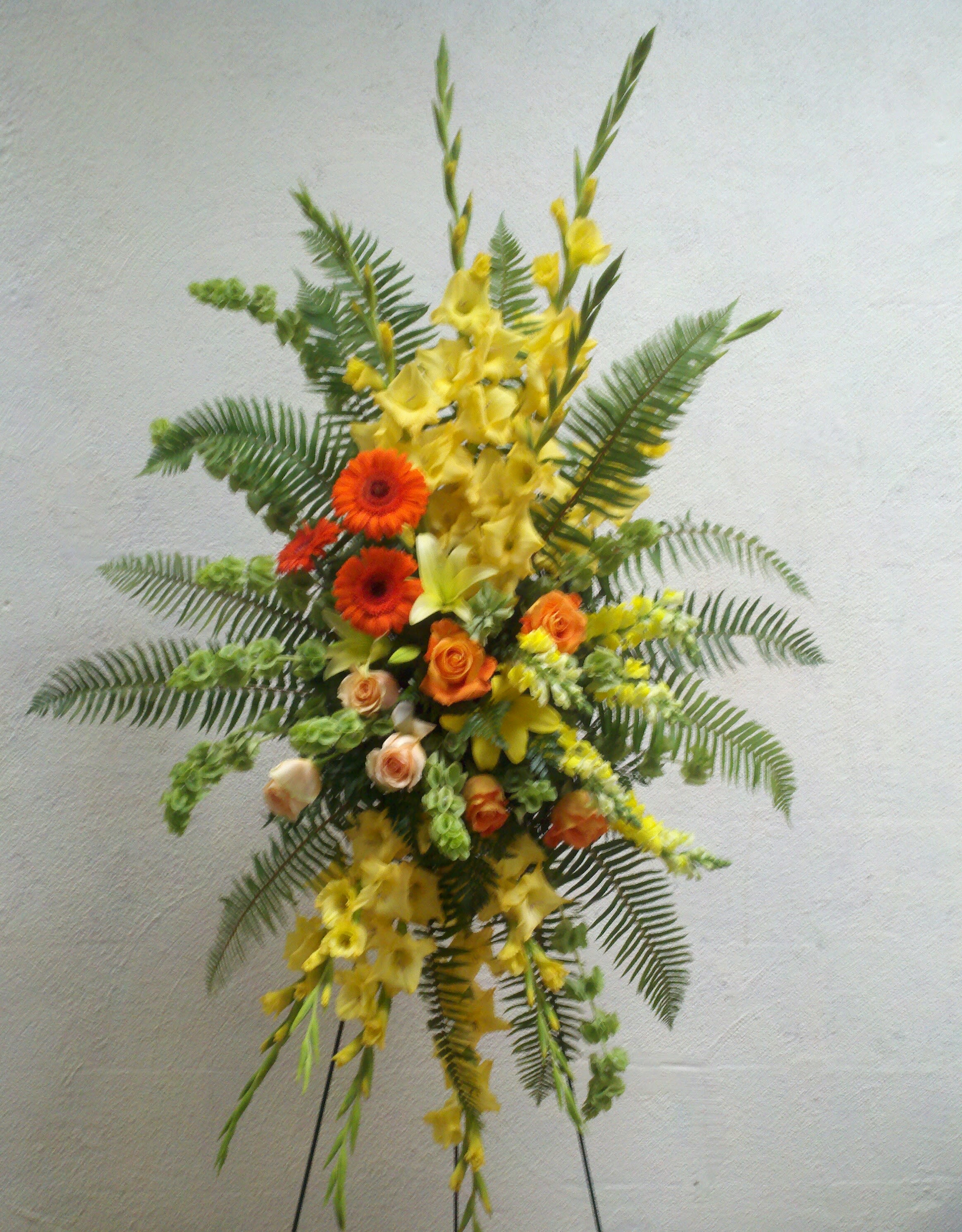Tall floral spray with yellow and orange flowers on a stand