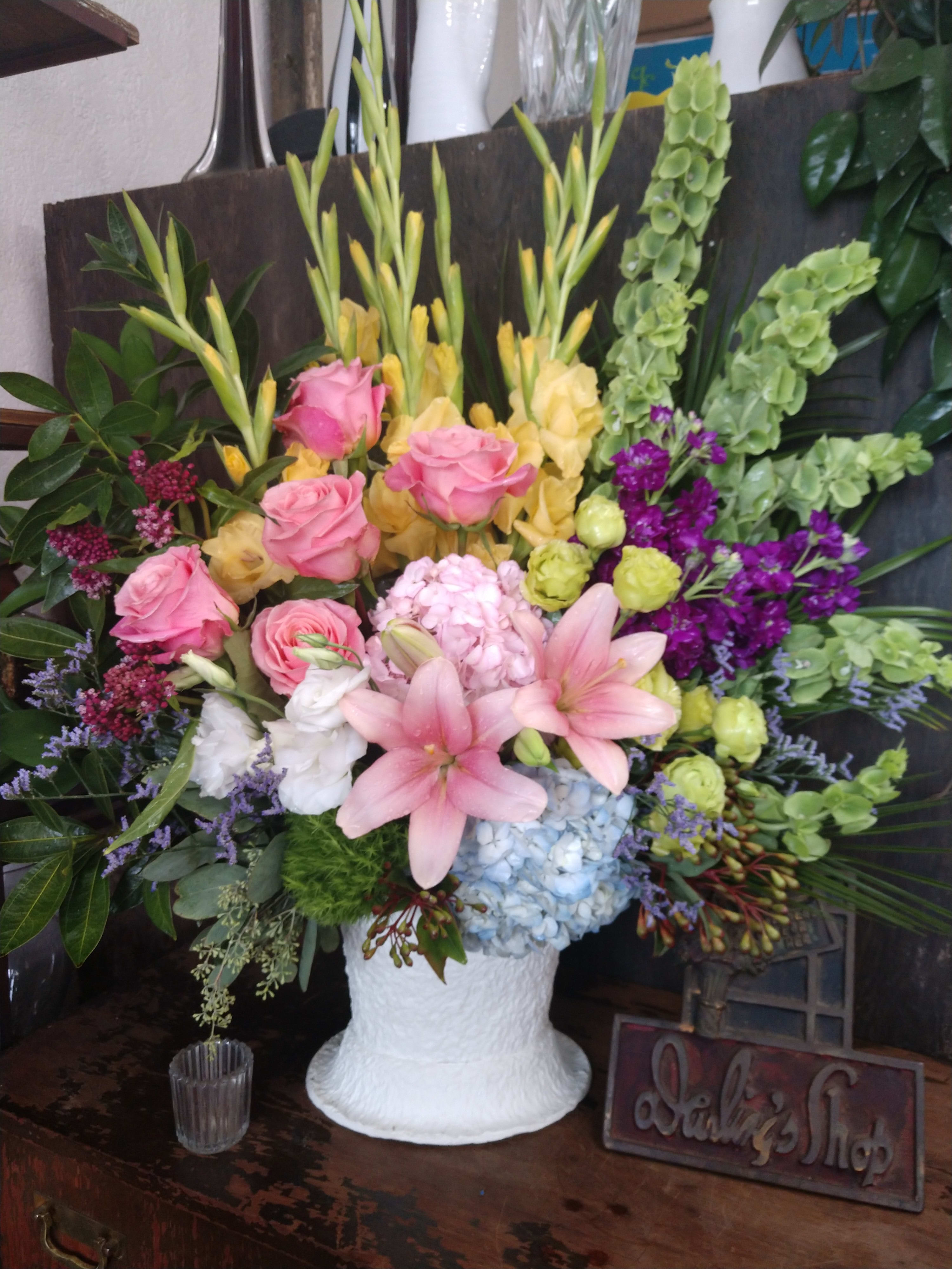 Mixed floral arrangement in a white vase with pink roses and lilies