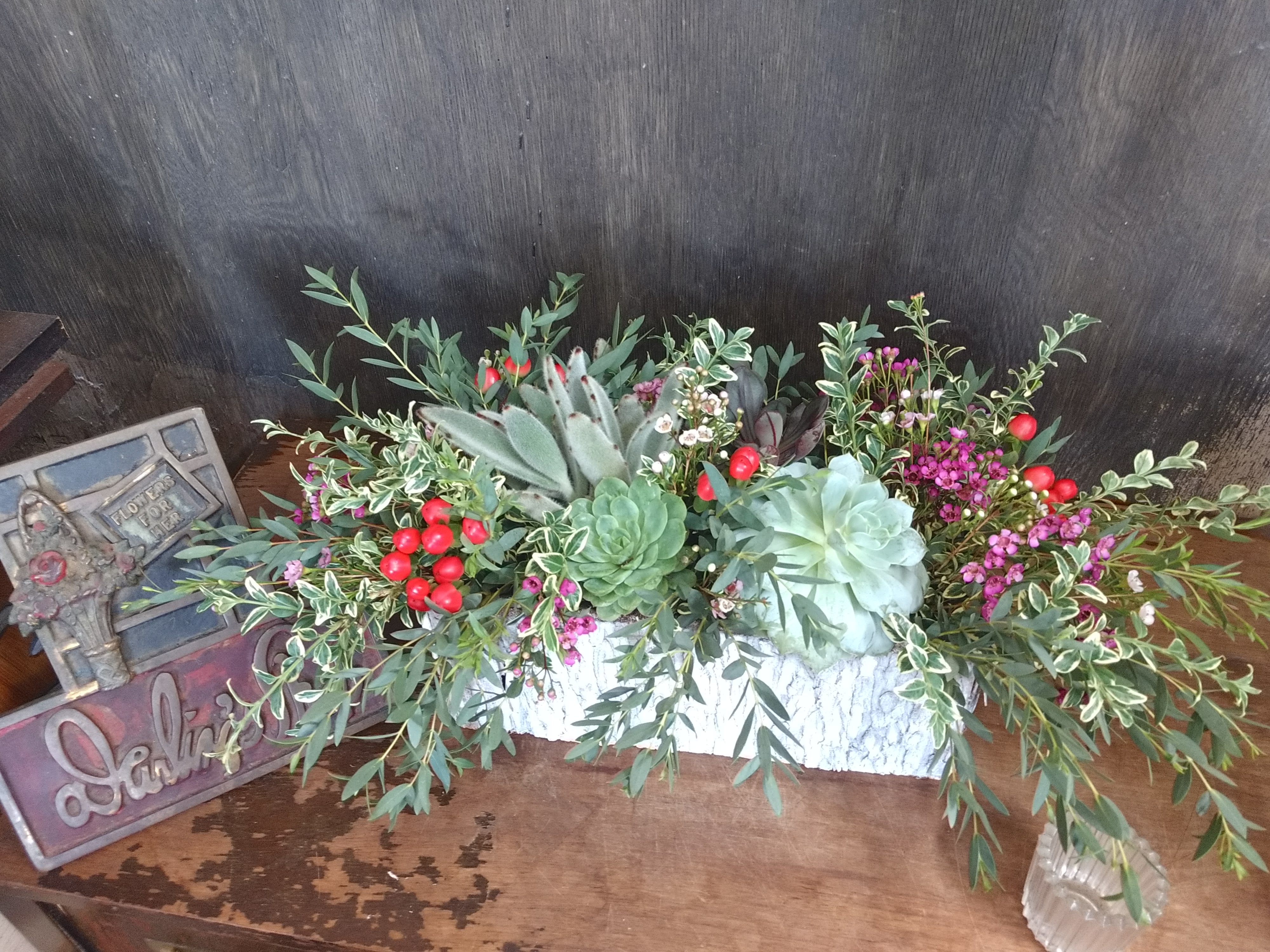 Succulent arrangement with red berries in a white container