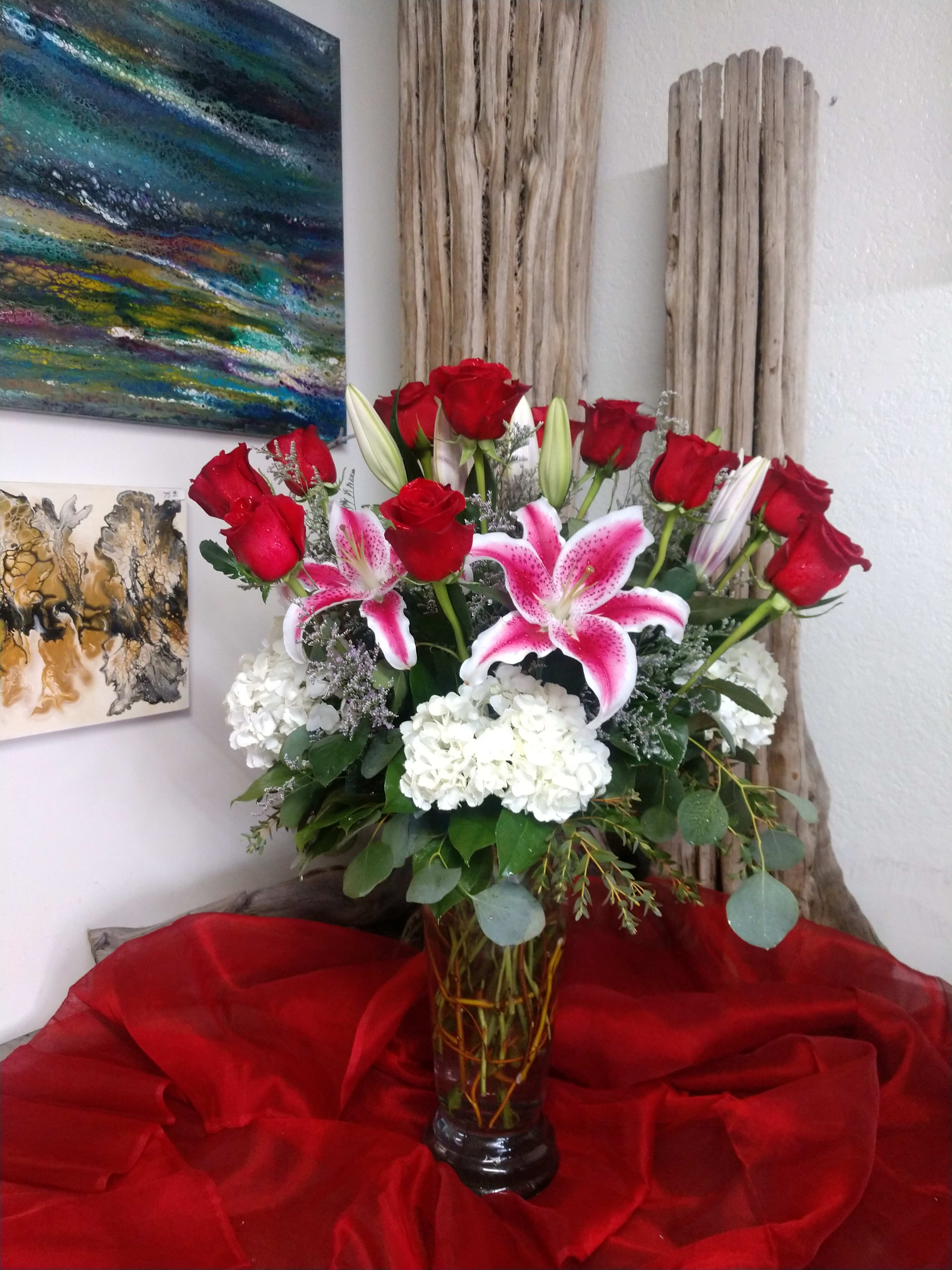Red roses and pink lilies arranged in a glass vase