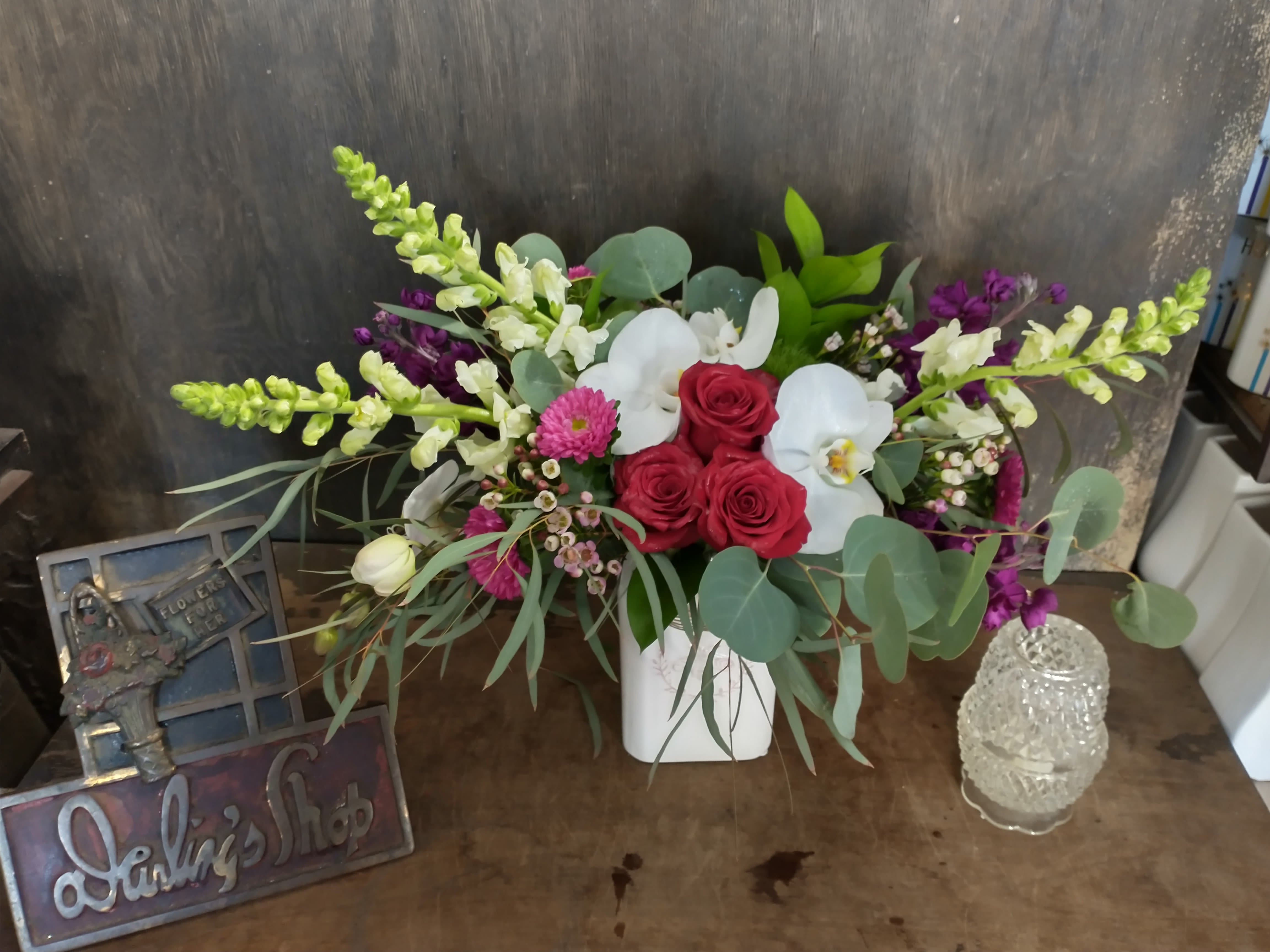 Arrangement of red roses and white orchids in a white vase