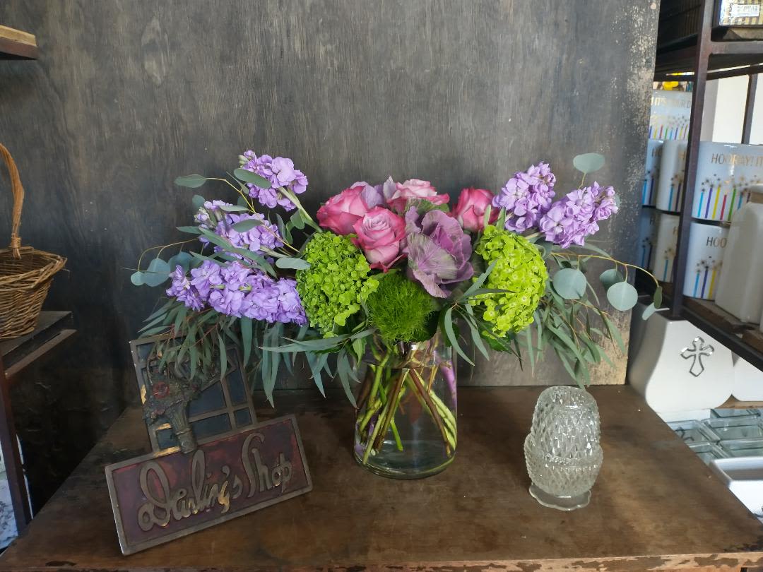 Bouquet of pink roses and purple flowers in a glass vase
