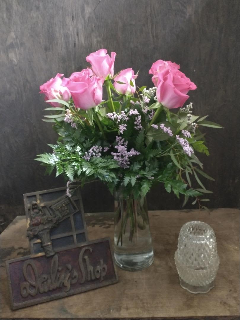 Pink roses in a glass vase with greenery and small filler flowers